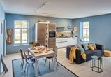 Modernes Wohnzimmer mit blauen Wänden, schwarzem Sofa, Esstisch und integrierter Küche mit LED-Deckenstrahlern.