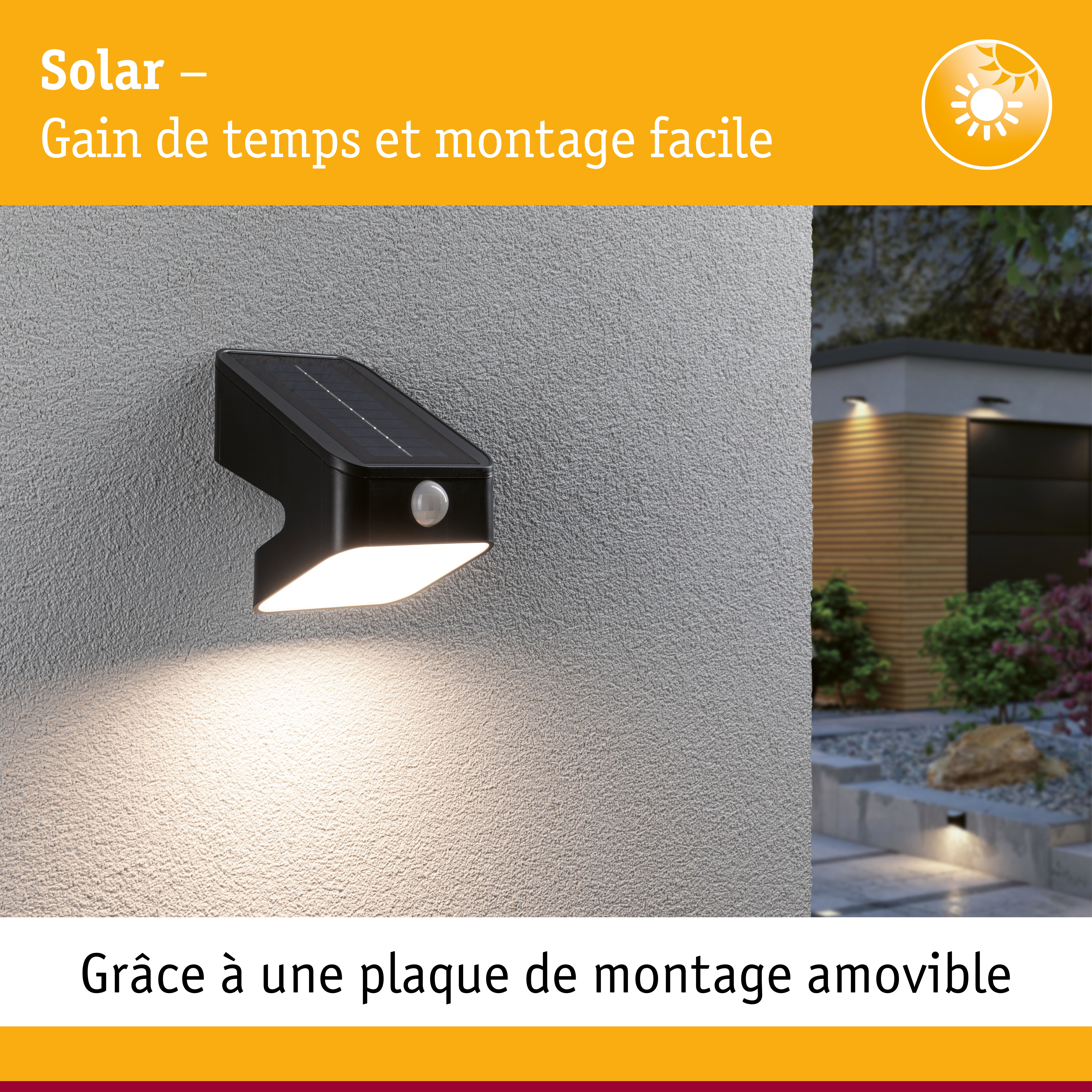 Applique murale solaire noire avec détecteur de mouvement sur mur gris éclairant un chemin de jardin au crépuscule