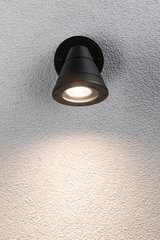 Black metal outdoor wall light with warm white LED illumination on textured wall surface
