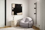 Fauteuil gris confortable avec cadre en métal noir à côté d'une lampe murale noire moderne à trois spots
