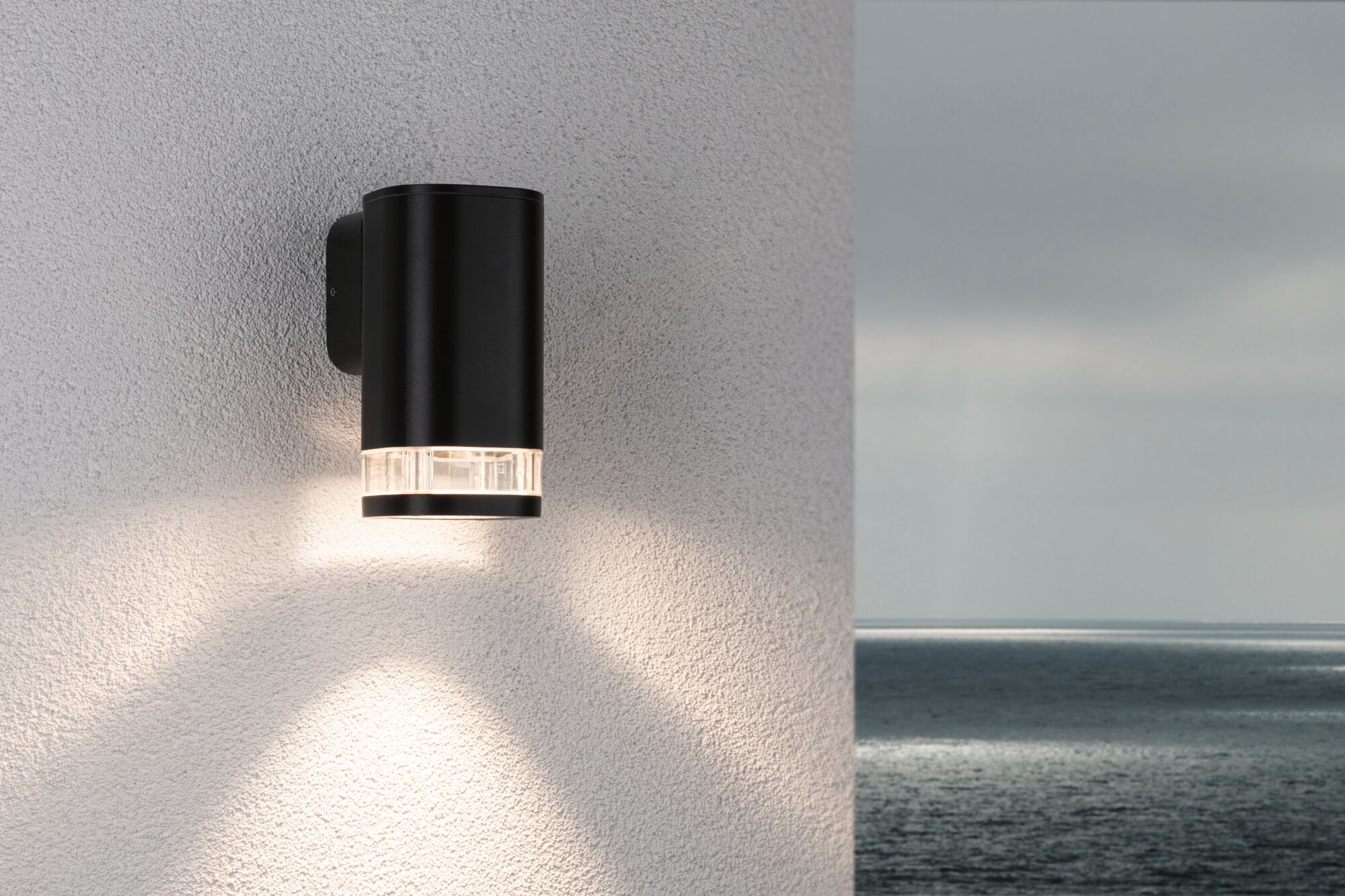 Zwarte metalen buitenwandlamp met helder glas en warm wit licht voor moderne gevelverlichting