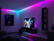 Salon avec bande LED bleue et rose au plafond pour un éclairage d'ambiance moderne