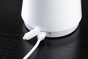Weißes elektrisches Gerät mit angeschlossenem Kabel auf schwarzer Holzoberfläche, Nahaufnahme des Anschlusses.