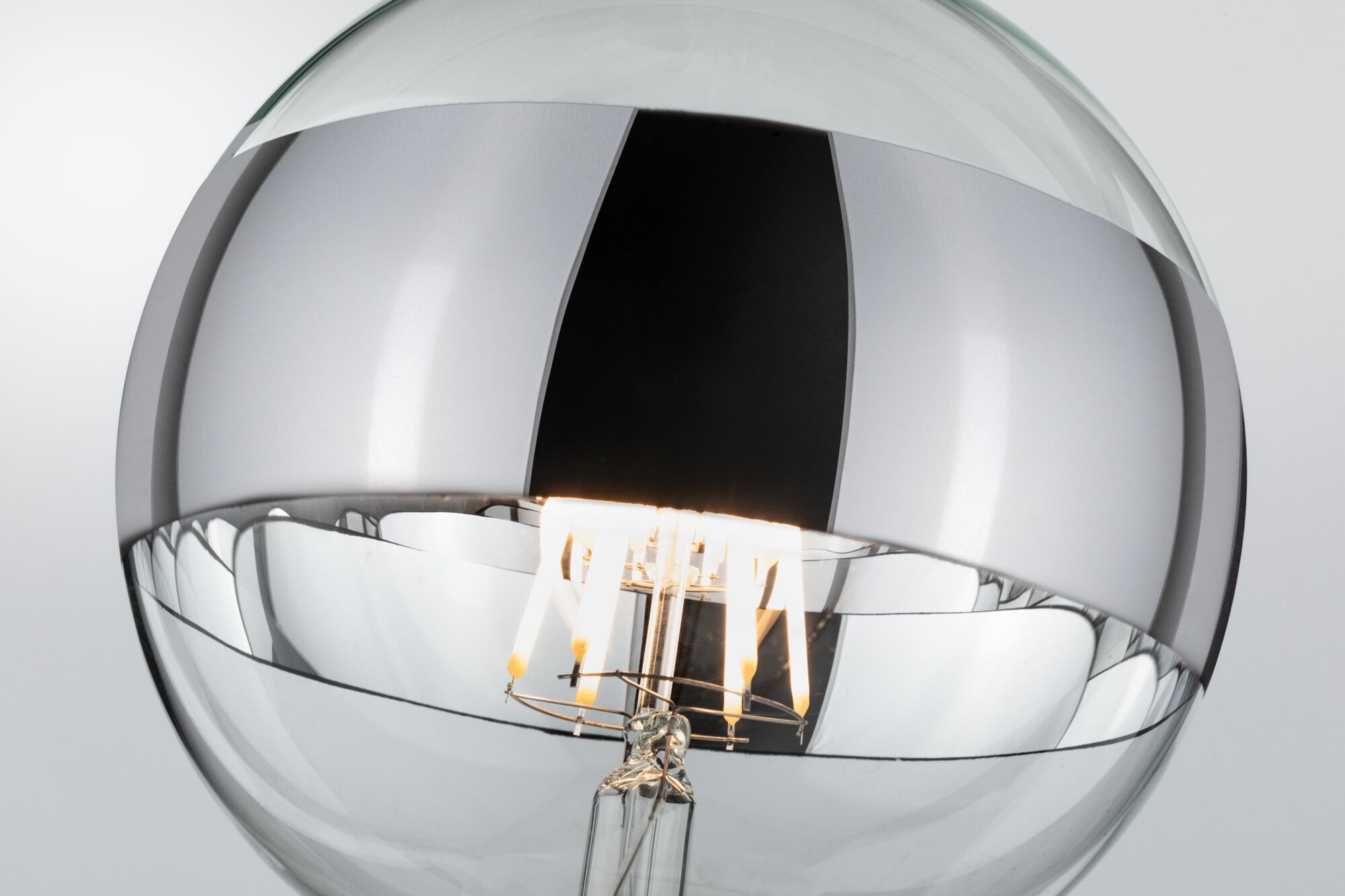 Gros plan d'une ampoule LED transparente avec filament visible et revêtement argenté pour éclairage moderne