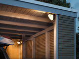 Außenwandleuchte mit warmweißem Licht an moderner Holzgarage, energiesparende LED-Beleuchtung.