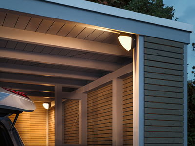 Außenwandleuchte mit warmweißem Licht an moderner Holzgarage, energiesparende LED-Beleuchtung.