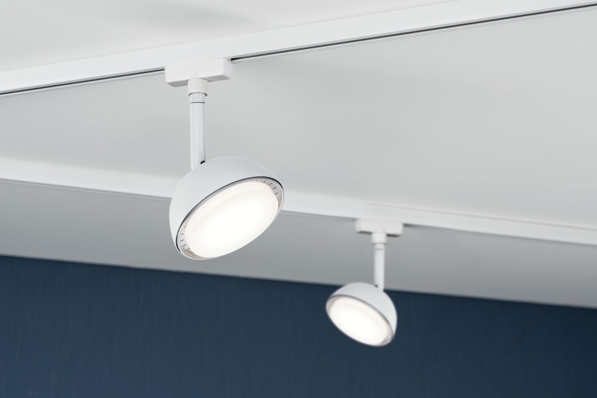 Two white metal LED spotlights on ceiling track system for modern room lighting