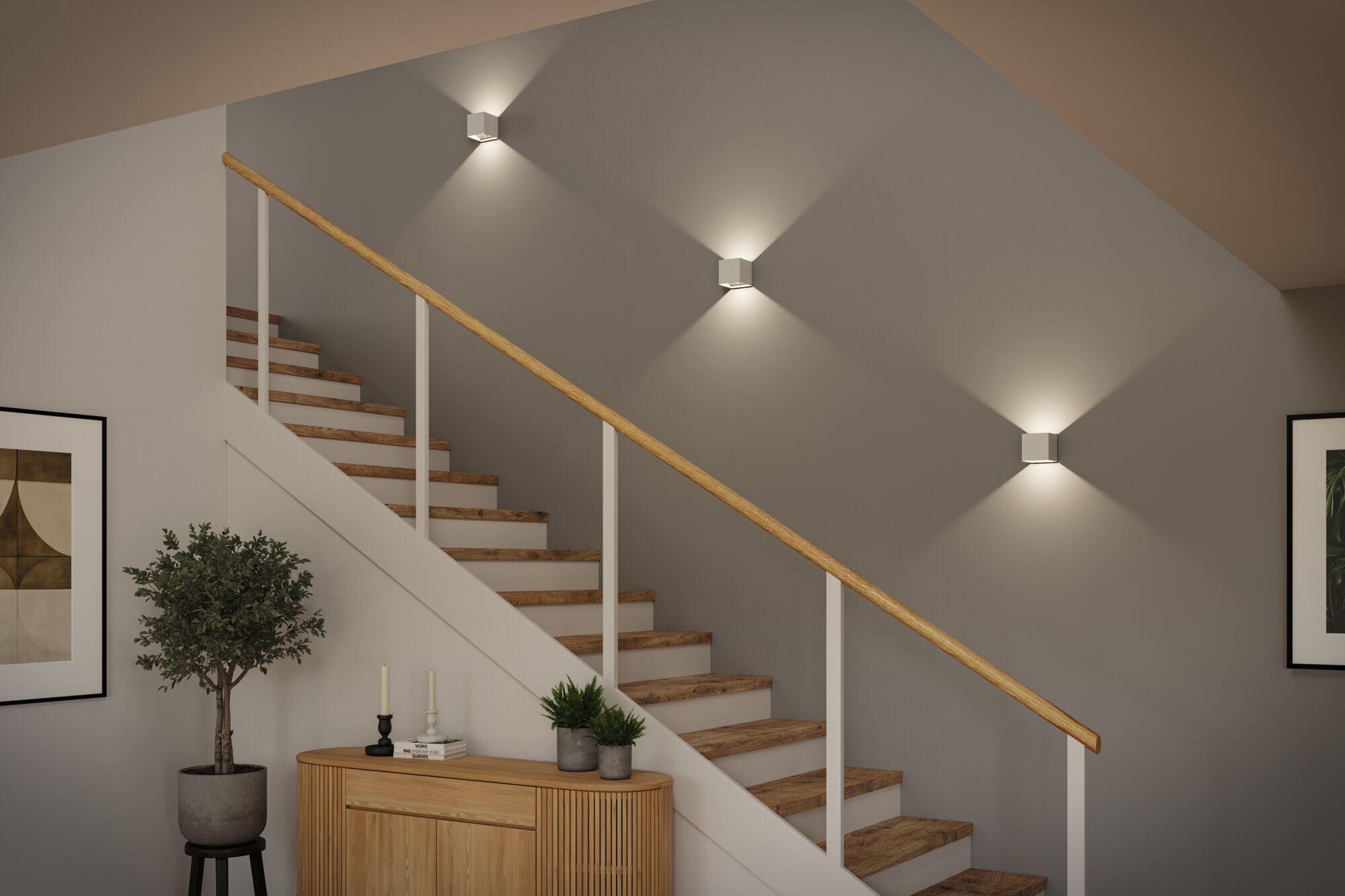 Three white metal LED wall lights on grey wall above wooden staircase with wood handrail