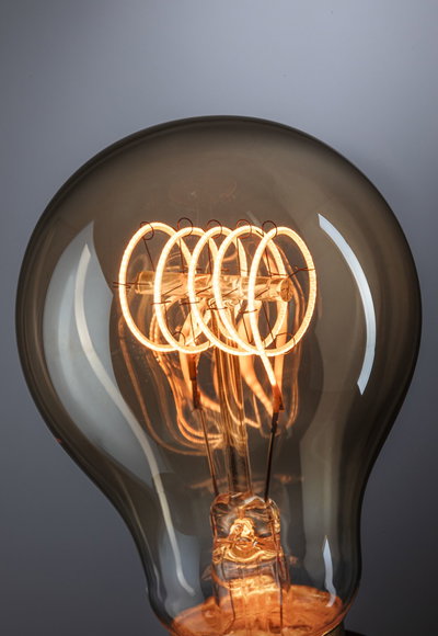 Nahaufnahme einer Glühbirne mit warmweißem LED-Filament in Rauchglas für dekorative Beleuchtung