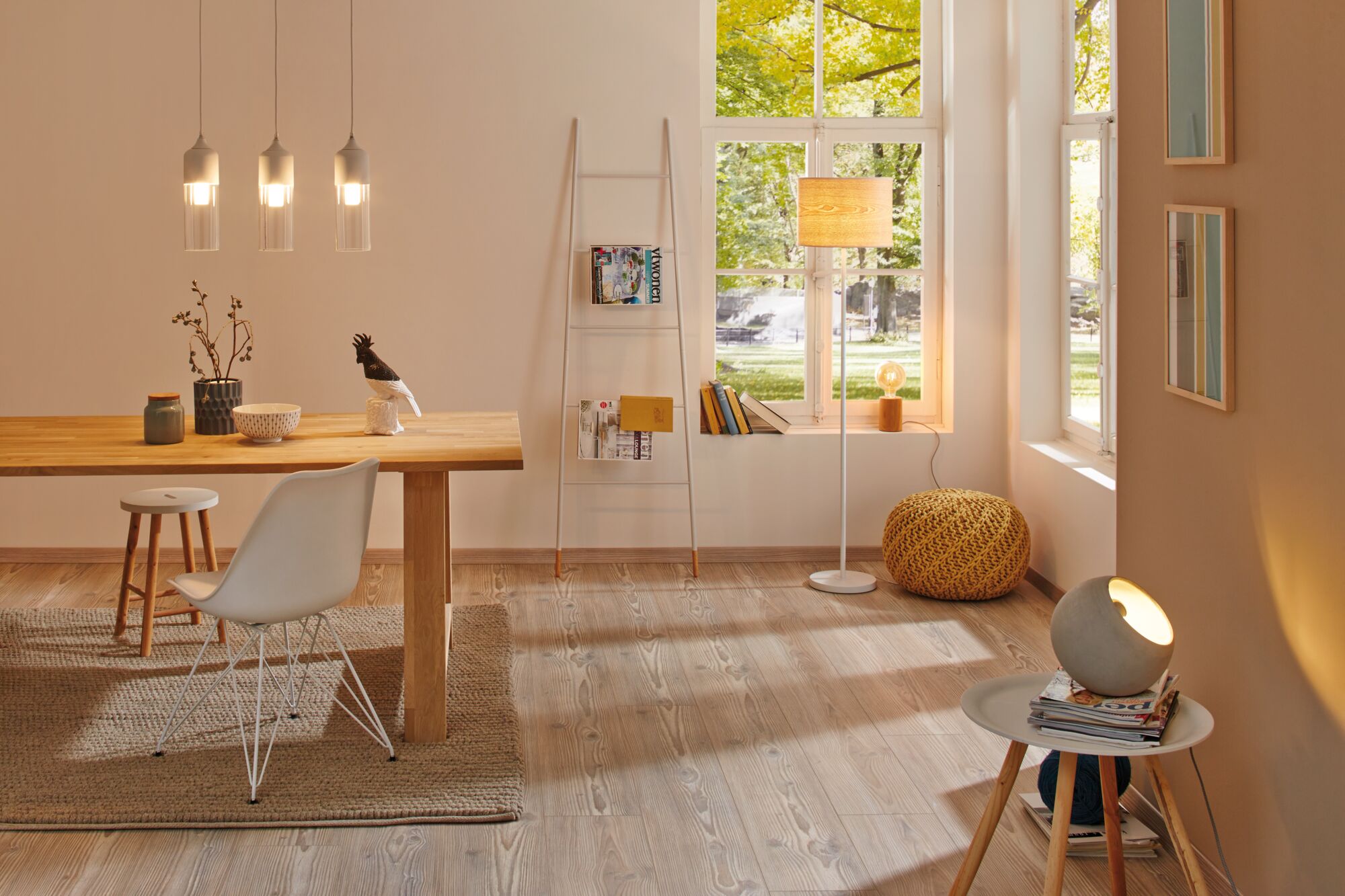 Salon lumineux avec sol en bois, lampadaire et suspensions modernes blanches et bois, design scandinave.