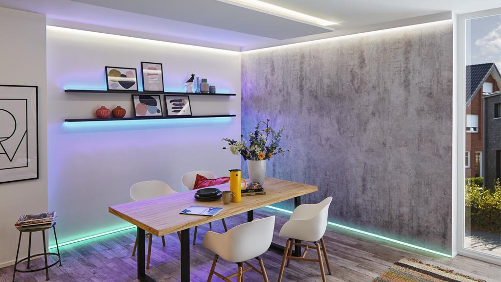 Modernes Esszimmer mit Holz-Tisch, weißen Stühlen und farbigen LED-Lichtleisten an Wand und Boden.