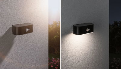 Black LED outdoor wall light with motion sensor, off by day and illuminated at night, modern garden lighting