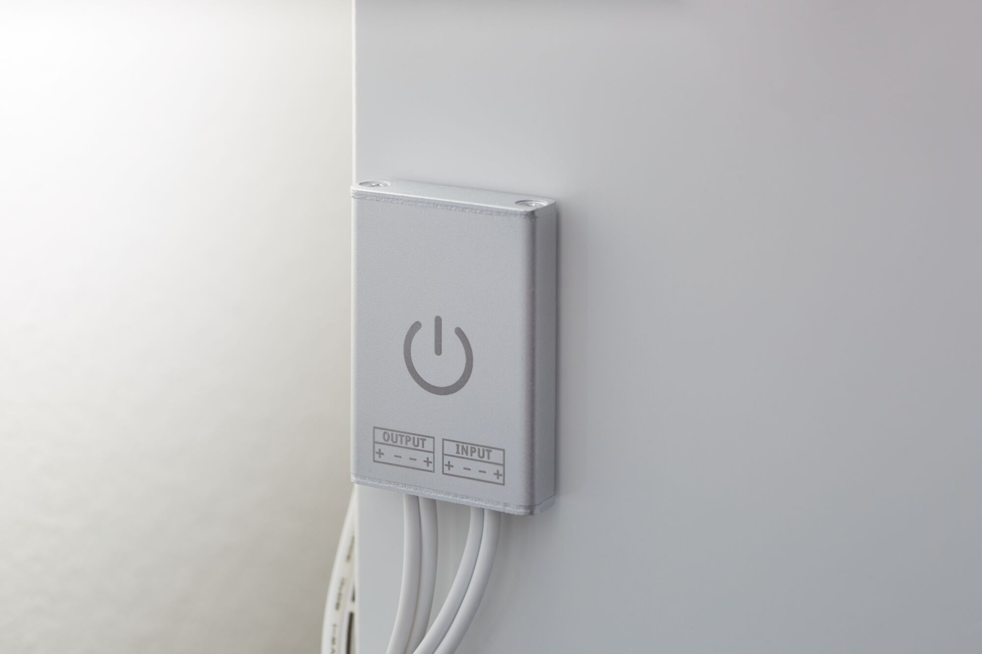 Compact silver LED switch with power symbol and white cables for lighting control