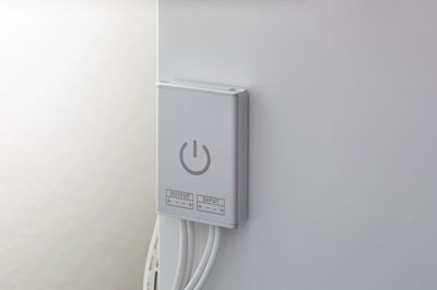 Compacte zilveren LED-schakelaar met aan/uit-symbool en witte kabels voor lichtregeling