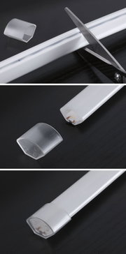 White LED aluminum profile strip with transparent plastic end caps on black surface for lighting setup