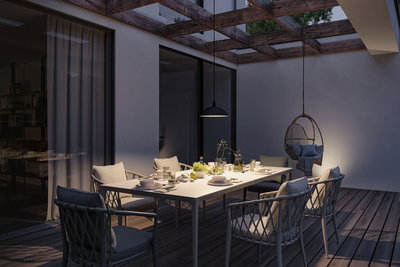 Moderne udendørs spiseplads med hvidt bord, grå stole og sort pendellampe til havebelysning