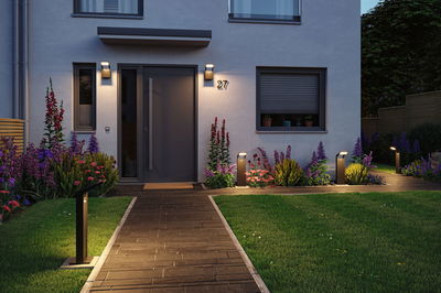 Moderne Außenbeleuchtung mit schwarzen LED-Wegeleuchten und Wandlampen an Hausfassade und Gartenweg
