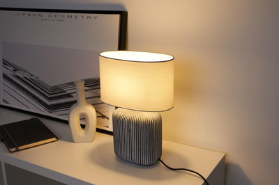 Moderne tafellamp met grijze keramische voet en ovale crèmekleurige stoffen kap voor sfeerverlichting