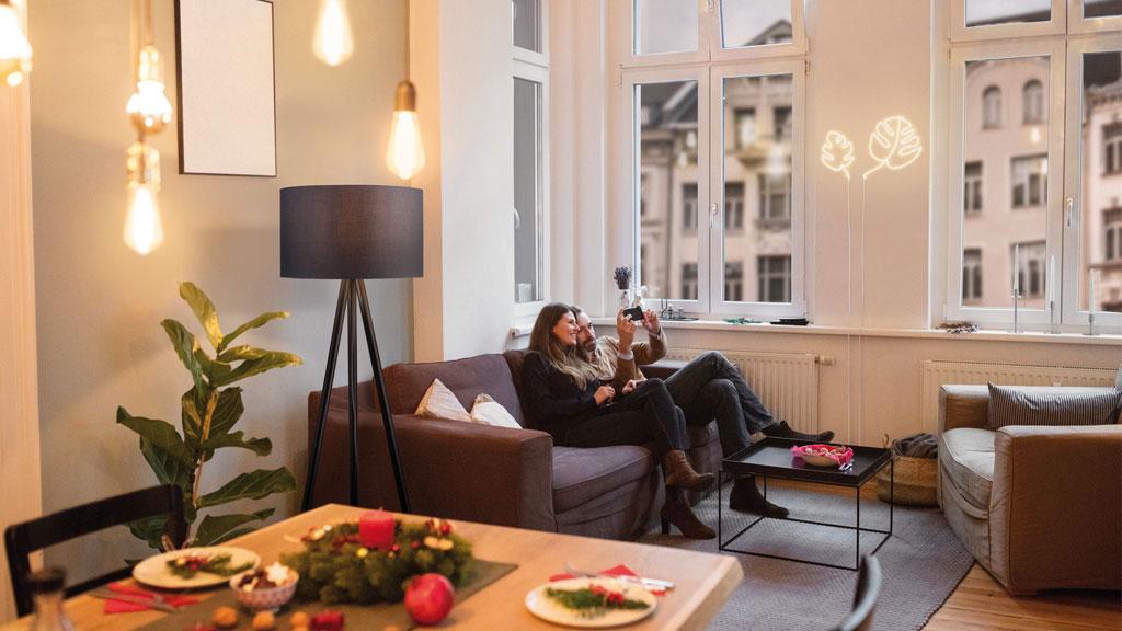 Cozy living room with black floor lamp, brown sofa, and Christmas table decoration with candles and wreath.