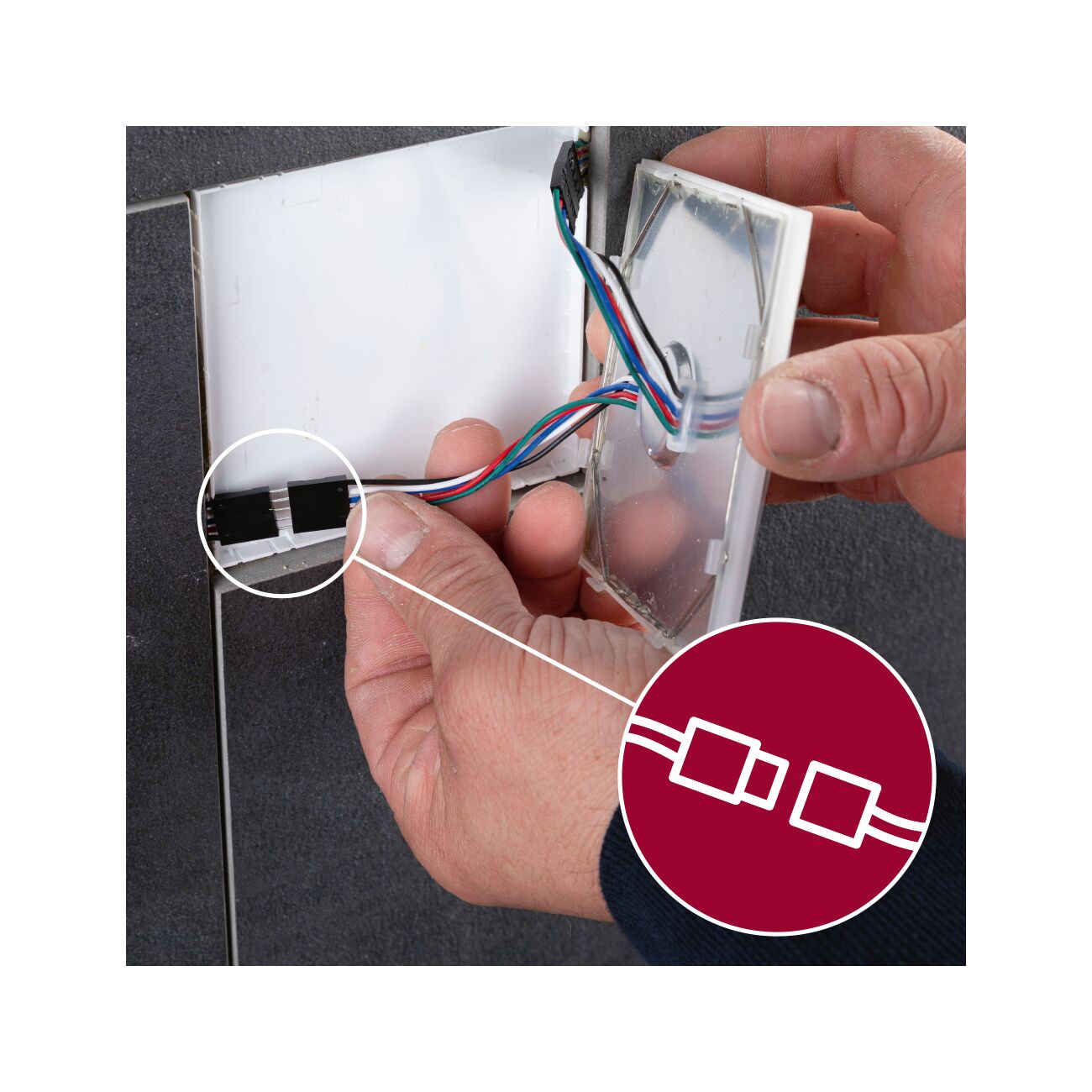 Main connectant des fils multicolores avec connecteur plastique blanc dans une ouverture murale pour éclairage LED.