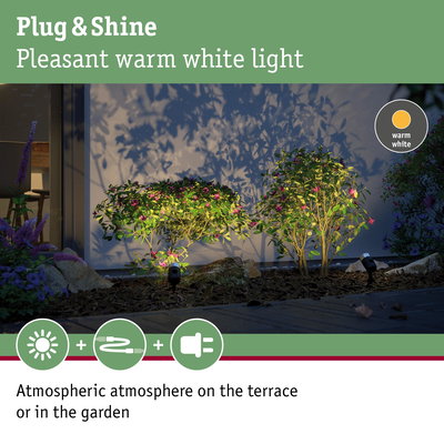 Plug & Shine warm white LED garden lights illuminating green shrubs with pink flowers at night