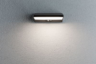 Black LED wall light with motion sensor on grey wall for outdoor lighting and security