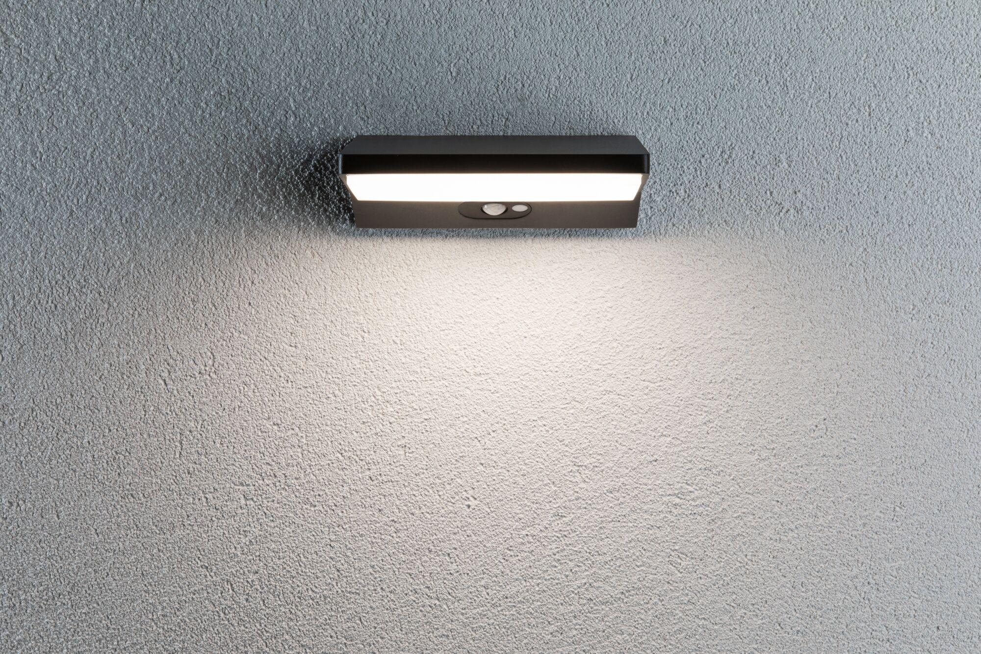 Black metal LED wall light with motion sensor on grey wall for outdoor lighting