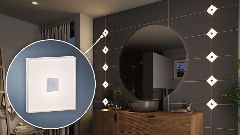 Moderne hvide firkantede LED-vægfliser i badeværelse med mørke fliser og træmøbler.
