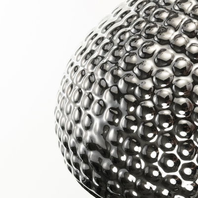 Close-up of a spherical lamp made of shiny, textured silver metal with LED lighting effect