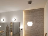 Suspension ronde moderne en verre blanc avec support métal sur mur en pierre beige dans salle de bain.