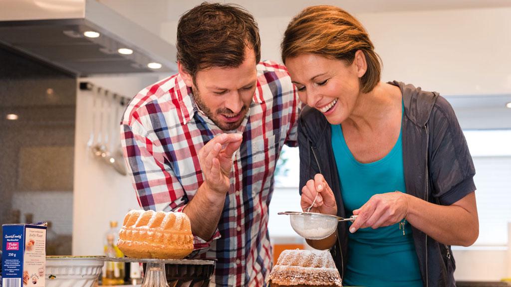 Paar beim Backen in moderner Küche mit heller LED-Unterbauleuchte für Küchenbeleuchtung.