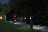 Modern black metal garden lights illuminate pathway with bench and plants at night