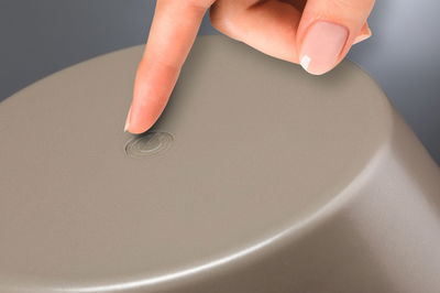 Finger berührt grauen Kunststoff-Schalter mit Ein-Aus-Symbol für elektronische Geräte