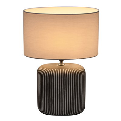 Table lamp with black striped ceramic base and light fabric shade for ambient room lighting