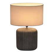 Table lamp with black striped ceramic base and light fabric shade for ambient room lighting