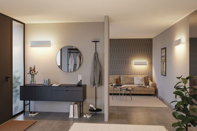 Moderne woonkamer met beige bank, zwarte dressoir en witte metalen wandlampen voor sfeerverlichting