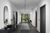 Modern hallway with white walls, grey rug, and black furniture lighting for living space design.