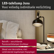 Zwarte LED-tafellamp Juna met verstelbare kap naast bank en boeken voor leeslicht