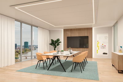 Modernes Büro mit rechteckigem weißen Tisch, orangen Stühlen und LED-Deckenbeleuchtung für Konferenzen