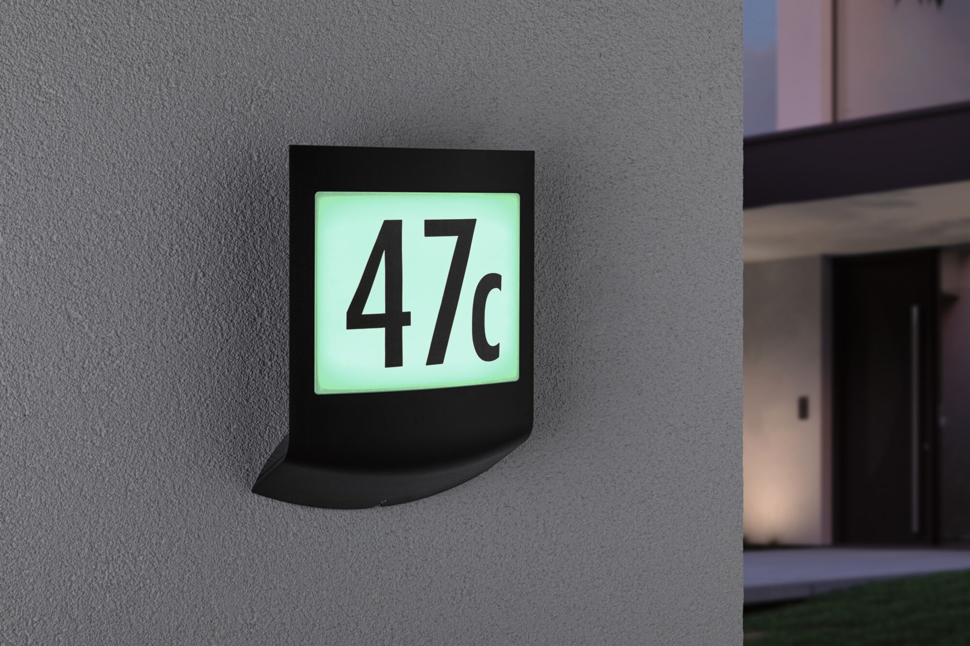 Zwart LED-huisnummerschild met verlicht wit-groen paneel met nummer 47c aan grijze muur