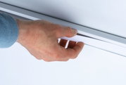 Main tenant une bande LED blanche en plastique contre un plafond blanc pour éclairage moderne