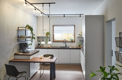 Modern white kitchen with wooden countertops and black pendant and track lighting for living space.