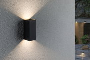 Applique murale noire en aluminium avec éclairage blanc chaud vers le haut et le bas sur mur extérieur gris