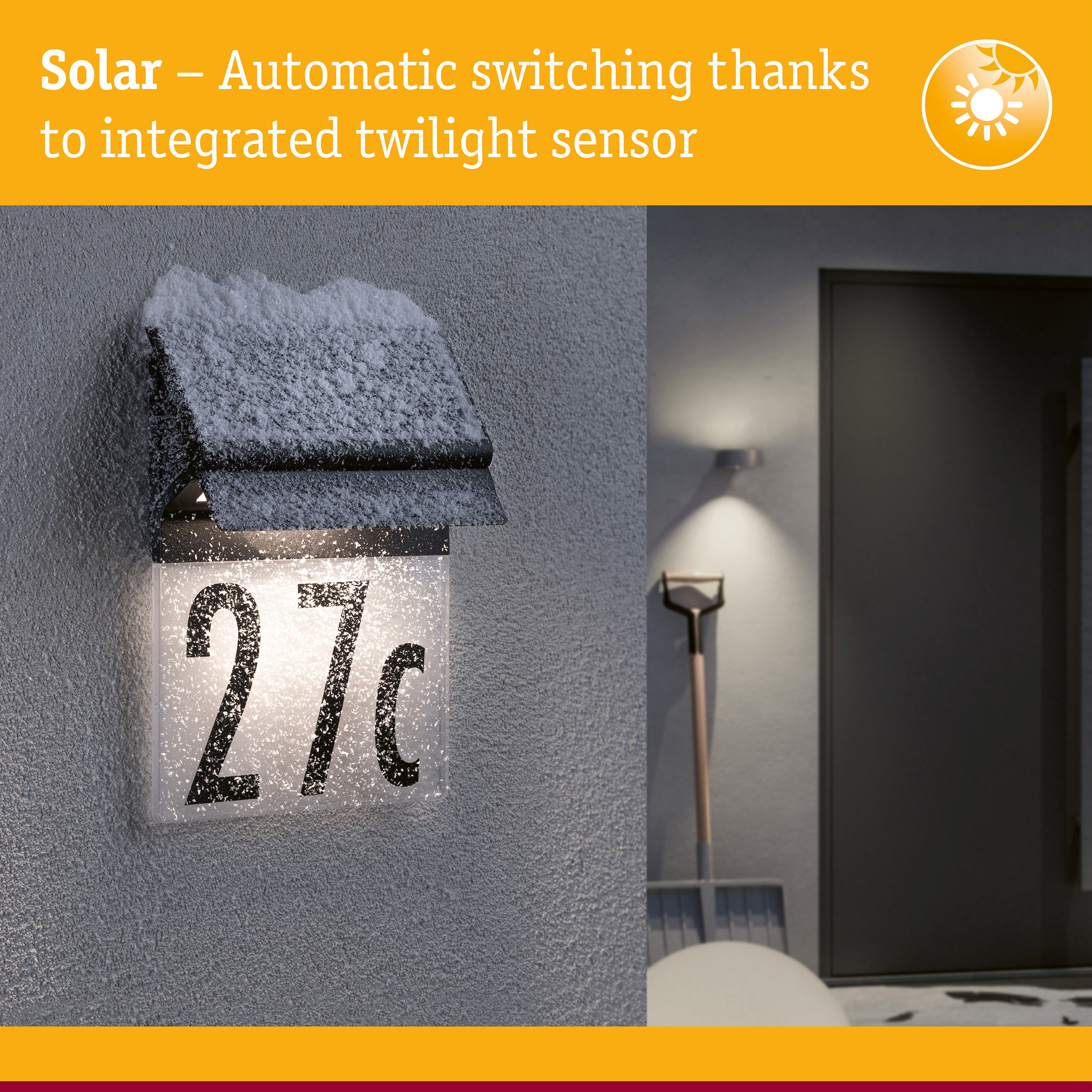 Black solar house number light with integrated twilight sensor covered in snow on grey wall