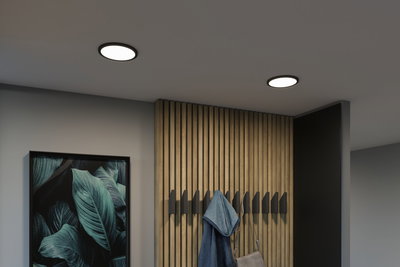 Luminaires LED ronds modernes au plafond avec cadre noir dans un couloir minimaliste en bois.