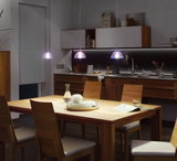 Cuisine moderne avec table à manger en bois et trois suspensions transparentes à éclairage LED.