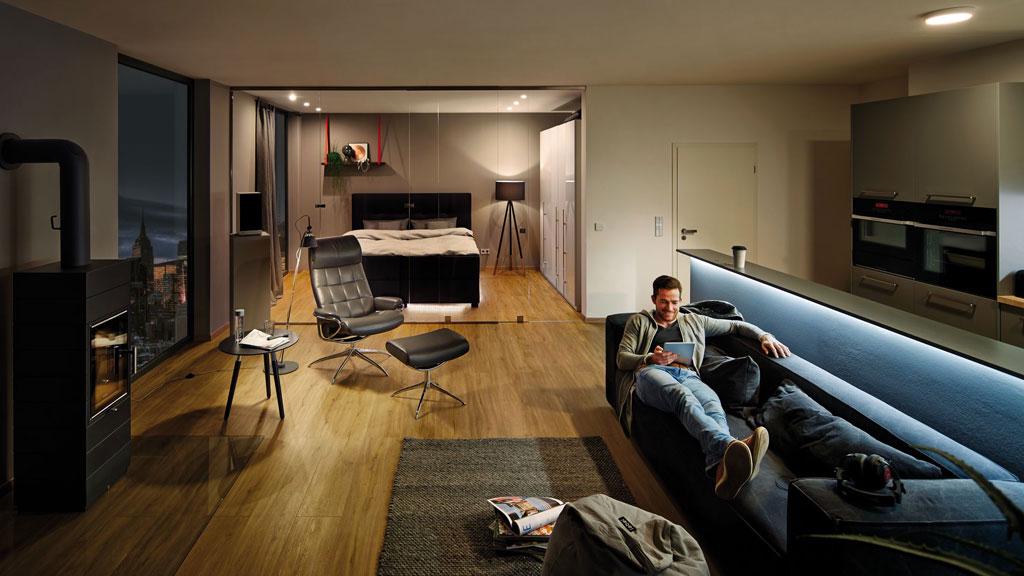 Appartement moderne avec bande LED intelligente dans salon et chambre, sol en bois clair.