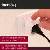 Witte kunststof smart plug in stopcontact met hand die knop indrukt, handmatige bediening