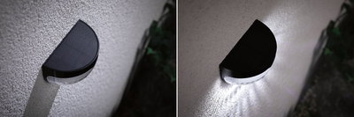 Schwarze halbrunde Solar-Wandleuchte aus Kunststoff an weißer Wand, Tag- und Nachtansicht mit LED-Licht.