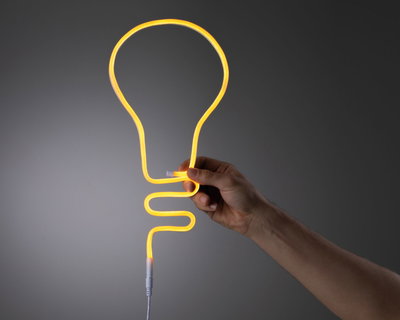 Hand hält flexibles gelbes Neonlicht in Glühbirnenform aus Kunststoff für dekorative LED-Beleuchtung